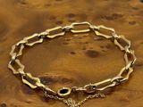 a close up of a gold bracelet on a wooden surface