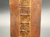 an old book sitting on a table with a green leaf sticking out of it