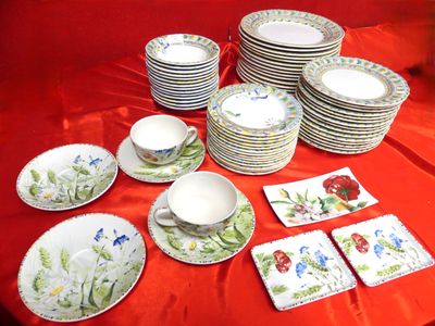 many plates and cups on a table with red cloth