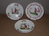 trois assiettes ornées de motifs représentant des oiseaux et des fleurs, posées sur une table