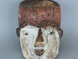 une image représentant un masque en bois coiffé d'un chapeau
