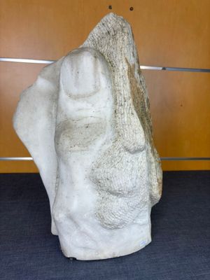 une grande sculpture en pierre représentant une tête, posée sur une table
