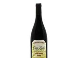 a bottle of red wine sitting on top of a white table