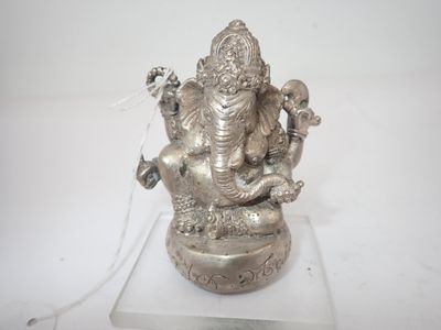 statue en argent représentant un Gan assis sur un serpent, posée sur un socle transparent