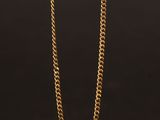 un collier à chaîne en or avec un fermoir carré sur fond noir