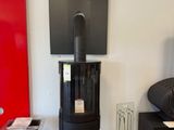 a black stove sitting in a living room next to a red wall