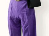 un mannequin vêtu d'un pantalon violet et tenant un sac à main noir