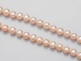 a close up of a strand of pink pearls on a white surface