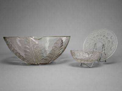 deux bols en verre et une assiette posés sur un support, le tout sur une surface grise