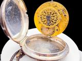 a gold pocket watch on a white plate on a black background