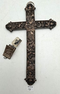 une vieille croix en métal, avec un briquet à côté, posée sur une surface blanche