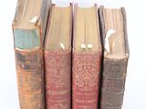 several old books are stacked on top of each other on a white surface