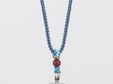 un collier bleu avec un pendentif carré et une chaîne en perles