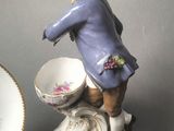a figurine of a boy holding a bowl and a plate