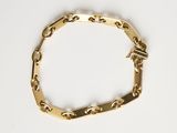 gros plan d'un bracelet en chaîne en or sur une surface blanche