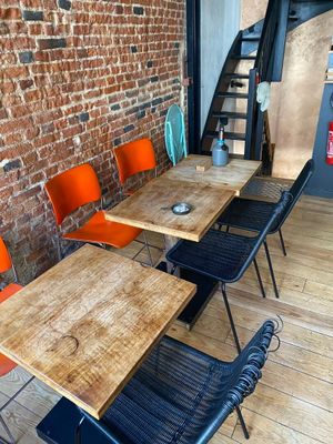 tables and chairs in a room with a brick wall and stairs
