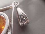 a close up of a pair of earrings with an orange stone