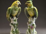 pair of green and yellow parrots sitting on a tree stump