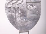 sculpture of a face made of metal on a stand on a white background