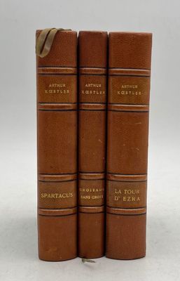 three brown books sitting on top of each other on a white surface