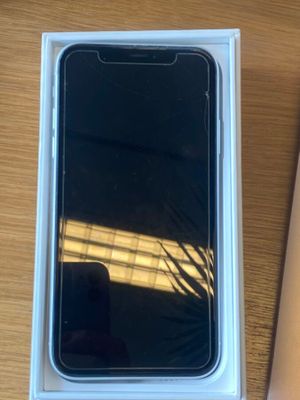 un iPhone dans une boîte posé sur une table à côté d'un ordinateur portable