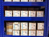 Des cartons contenant du matériel électronique sont empilés sur des étagères dans un entrepôt