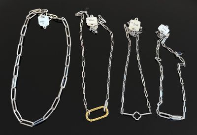 un ensemble de quatre colliers en argent et en or sur un fond noir