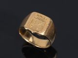 a close up of a gold ring with a coat of arms on it