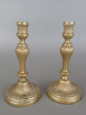 pair of antique brass candlesticks on a grey background