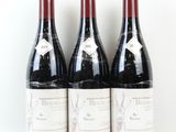 trois bouteilles de vin rouge sont alignées sur une surface blanche