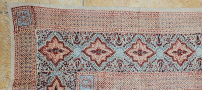 un vieux tapis aux motifs bleus et rouges posé sur un parquet