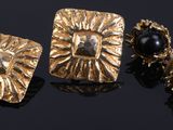 deux paires de boucles d'oreilles plaquées or, ornées de pierres noires sur un fond noir