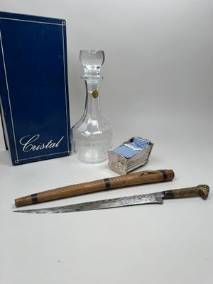 a glass bottle, a knife, and a box of matches on a table