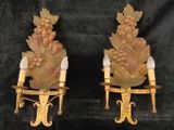 two golden sconces with flowers on them on a black background
