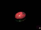 a red stone sitting on top of a black surface in the dark
