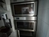 trois fours dans une petite cuisine, avec une poubelle devant eux