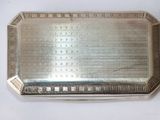 a silver plate with a design on it on a white surface