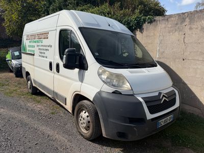 une camionnette blanche garée près d'un mur, avec des arbres en arrière-plan