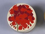 two tins with red flowers on them sitting next to each other