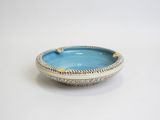 a blue bowl with a gold rim on a white table