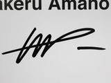 an autograph of a person holding a cell phone in front of a sign
