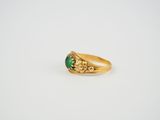 a gold ring with a green stone in the center