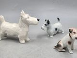 trois petites figurines représentant des chiens assis par terre