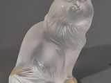 une figurine de chat blanc posée sur une surface grise