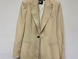 un blazer beige à fines rayures, suspendu à un cintre devant un mur blanc