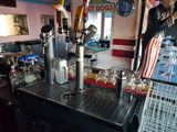 a man that is standing behind a bar with a bunch of drinks