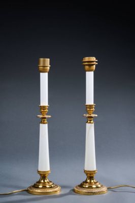 a pair of white and gold candles sitting on top of a table