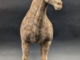 statue of a horse standing on a wooden base against a black background