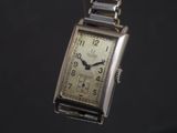 a watch that is hanging from a chain on a black background
