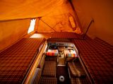 a bed in a tent with a red and yellow blanket